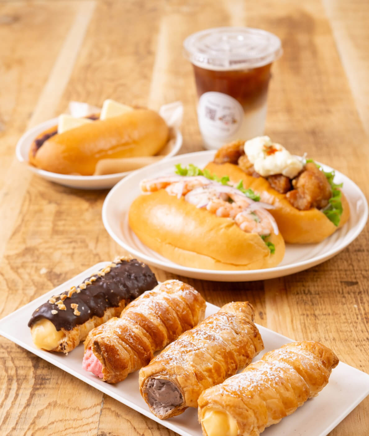 チキン南蛮やえびアボカドのこっぺパンと、クリーム入りのコルネ、アイスコーヒーが並ぶセット